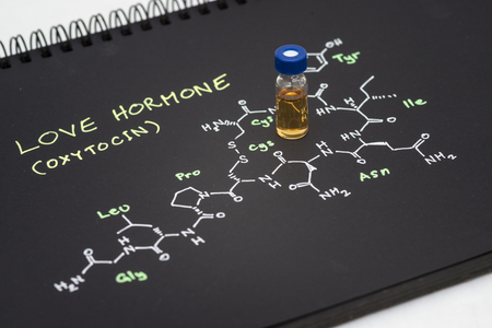 Close-up blue cap sample vial on notebook with chemical formula of Oxytocin (love hormone)の写真素材