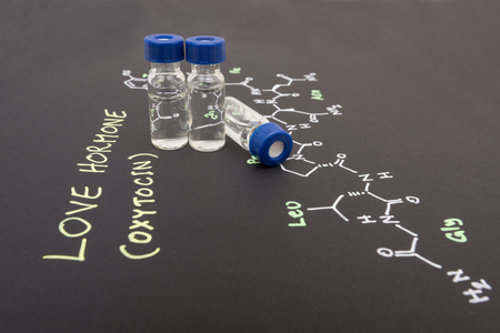 Close-up blue cap sample vial on paper with chemical formula of Oxytocin (love hormone)の写真素材