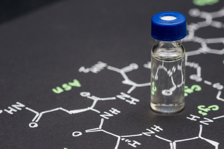 Close-up blue cap sample vial on paper with chemical formula of Oxytocin (love hormone)の写真素材