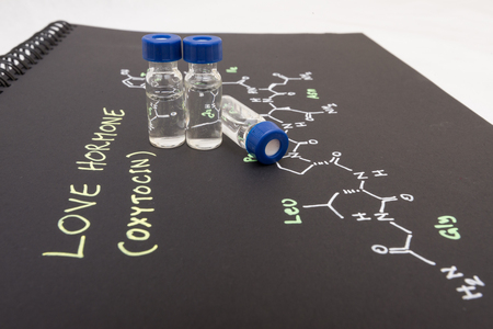 Close-up blue cap sample vial on paper with chemical formula of Oxytocin (love hormone)の写真素材