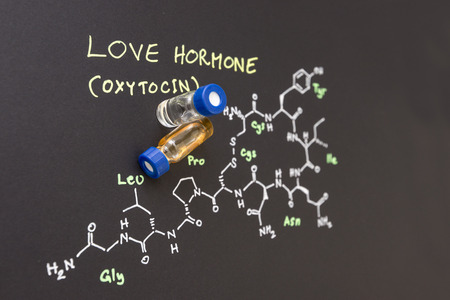 Close-up blue cap sample vial on paper with chemical formula of Oxytocin (love hormone)の写真素材