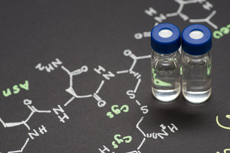 Close-up blue cap sample vial on paper with chemical formula of Oxytocin (love hormone)の写真素材