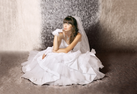The bride with a thoughtful expression on his face in a wedding dress in a sitting positionの写真素材