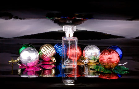 Women's perfume bottle with colored Christmas balls on a black backgroundの写真素材