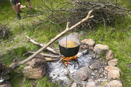 Cooking soup in a tourist camp cauldron on a fire in the afternoon in the springの写真素材