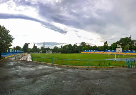 Wet football field without football players and without spectators in cloudy weather in the city of Krivoy Rog in Ukraine in the summerの写真素材
