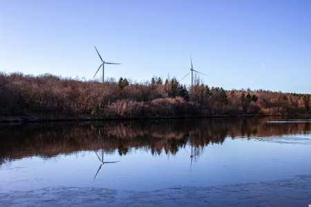 Windmill near the beautiful lake with a blue clear skyの写真素材