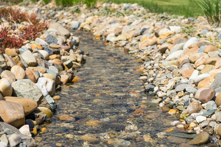 Small calm stream. Stream surrounded by rocks. Soft focus. Small river close up. Stones and rocks with stream.の写真素材