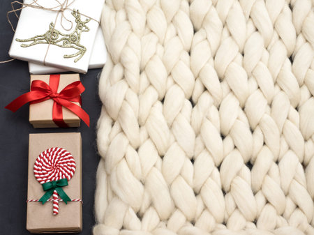 Cozy composition, closeup merino wool blanket, warm and comfortable atmosphere. Knit background. Wrapped gifts. Christmas concept.の写真素材