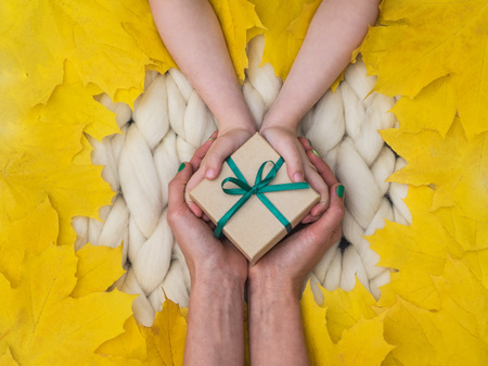Cozy composition, Wrapped gift on merino wool blanket, warm and comfortable atmosphere. Knit background. Flat lay. Top view. Copy space. Autumn concept.Wrapped giftの写真素材