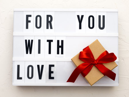 FOR YOU WITH LOVE word on lightbox on knit background with wrapped gifts boxes. Valentine's day...