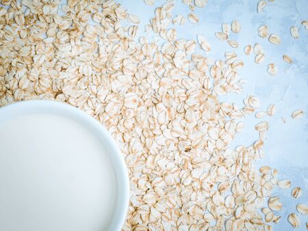 Oat milk drink in white cup and cereal flakes on kitchen bench. Flat lay. Copy space.の写真素材