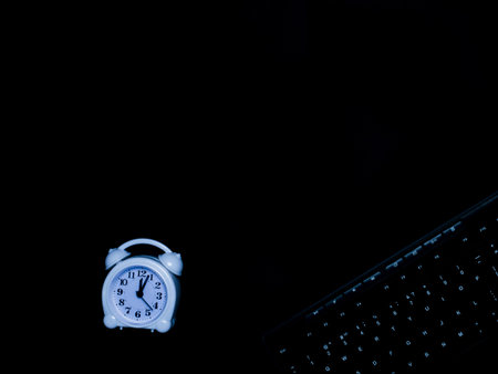 Minimal black work space concept: White alarm clock, keyboard, top view