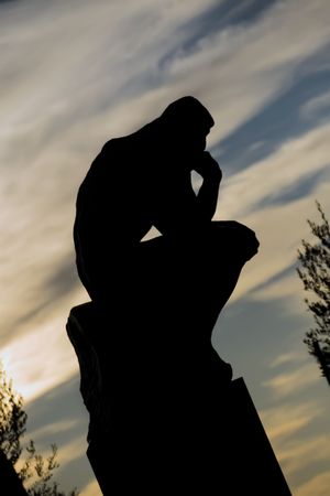 A famous Auguste Rodin's statue, "The Thinker", a man seated in a thinking position, hand on chin. Here with backlit shot, as a silhouette, taken at Saint Paul de Vence, on french riviera.の写真素材