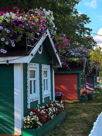Green and red houses with intricate design and colorful flowers against a white picket fence. High quality photoの写真素材