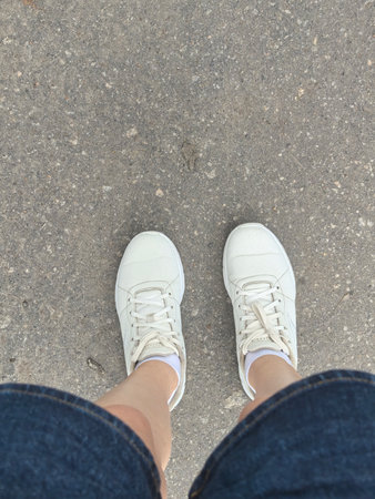 The feet of a man in white sneakers standing on the sidewalk. High quality photoの写真素材
