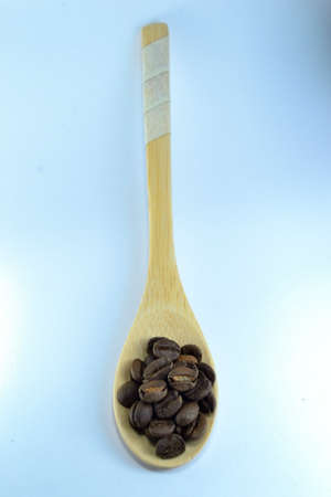 Coffee beans in a bamboo spoon. Photo with white background blurの写真素材