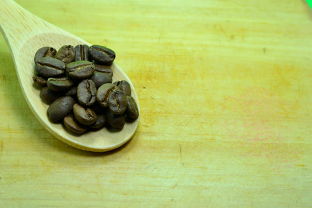 Coffee beans on a stencil spoon on a green background