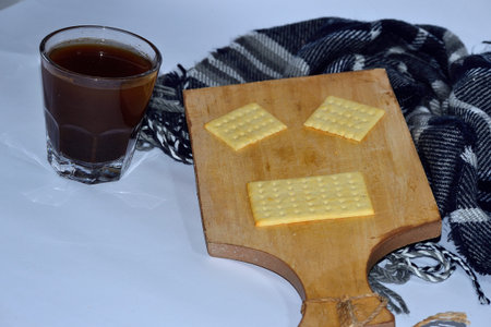 Cup of tea and cookies on a wooden board with a scarf