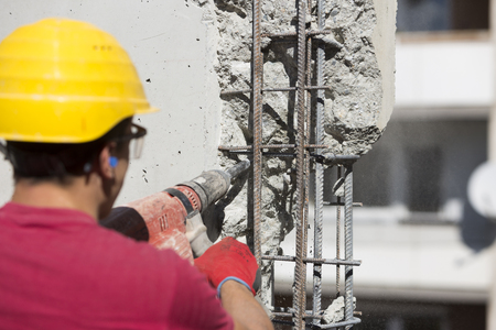 Worker using a drilling power tool on construction site and creating holesの写真素材