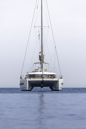 White sailing boat catamaran on ocean near beach.の写真素材
