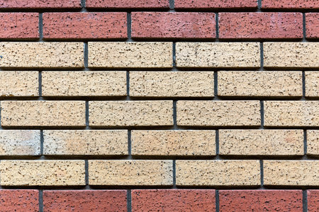 Red and beige painted brick wall background texture close up.