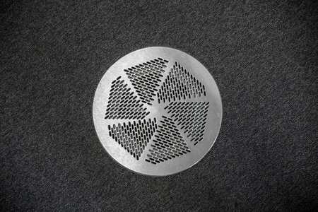 Close Up of Circular Metal Air Vent in Home Surrounded by Carpet Floor.