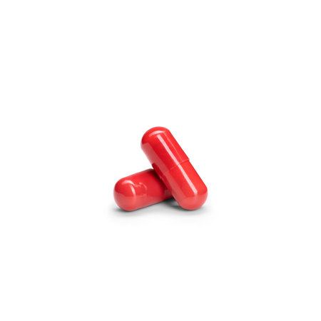 Close-up of a couple pills or capsules color red on isolated white background.