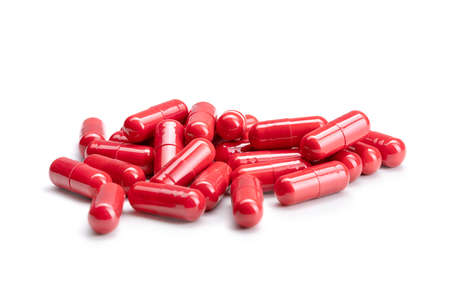 Close-up of a pile of red colored pills or capsules on isolated white background. Selective Focus.の写真素材