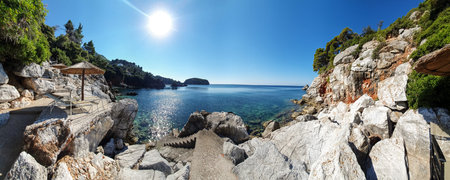Pristine bay Panorama View of a Greece Island with empty sun loungers and beach umbrellas.の写真素材