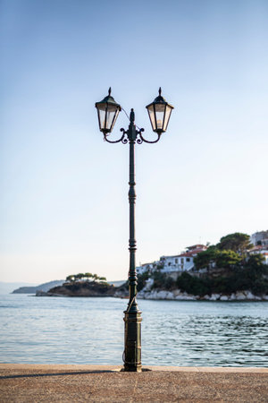 Single street lamp on the pier seafront with flowing water at sunset.