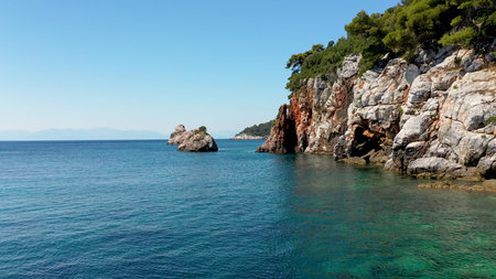 Aerial drone views over a rocky coastline, crystal clear Aegean sea waters, touristic beaches and...