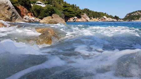 Small waves splashing on the rocks at sunset.の写真素材