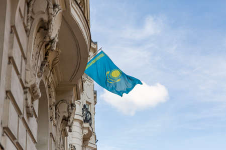 Kazakhstan flag agains blue sky. Kazakhstan flag hanging on a pole in front of the house. National flag waving on a home displaying on a pole on a front door of a building.の写真素材