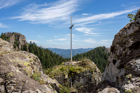 View on coniferous woods and Rocky mountains in Bulgaria with cross on top of it.の写真素材