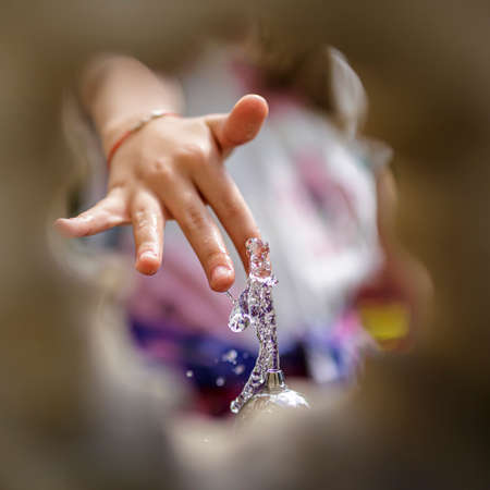 Childs hand playing with drinking water running from an old water pump.の写真素材