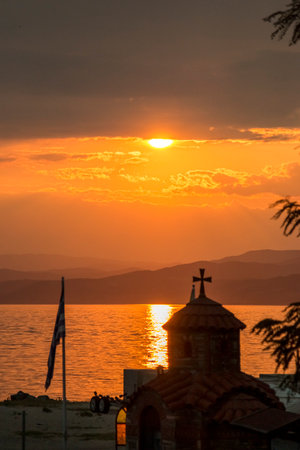 Golden sunset over a serene sea, with gentle waves and clouds illuminated by the warm evening glow.の写真素材