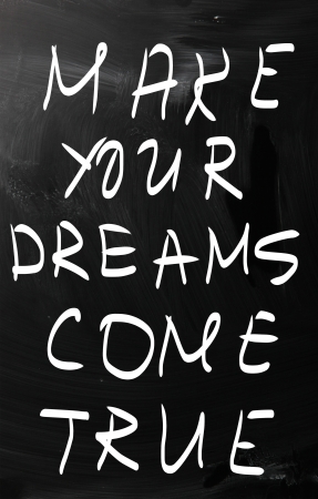 "Make your dreams come true" handwritten with white chalk on a blackboardの写真素材