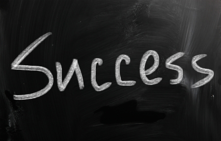 The word 'Success' handwritten with white chalk on a blackboardの写真素材