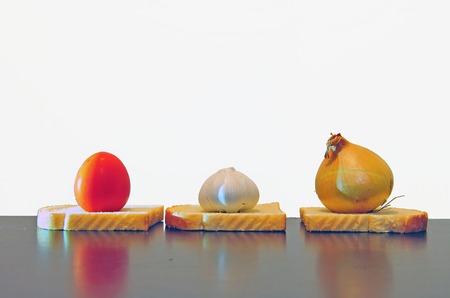 Garlic, onion and tomato on the tableの写真素材