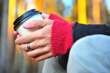 Hands with a coffee cup, outdoor sceneの写真素材