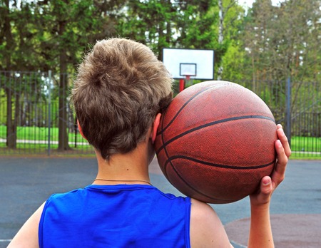 Young basketball player with a ball on his shoulder on the courtの写真素材