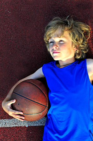 Young basketball player holding a ball outdoorsの写真素材