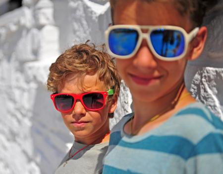 Two kids wearing sunglasses at white wallの写真素材