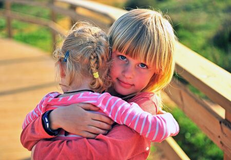 Happy little blond boy hugging his sister outdoorsの写真素材