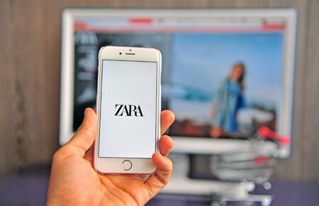 Yaroslavl, Russia - August 14, 2019: Hand with smartphone showing Zara new logo and website on background on August 14, 2019.のeditorial素材