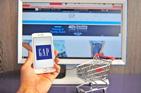 Yaroslavl, Russia - August 14, 2019: Hand holding mobile phone with Gap logo and retailer's website on background on August 14, 2019.のeditorial素材