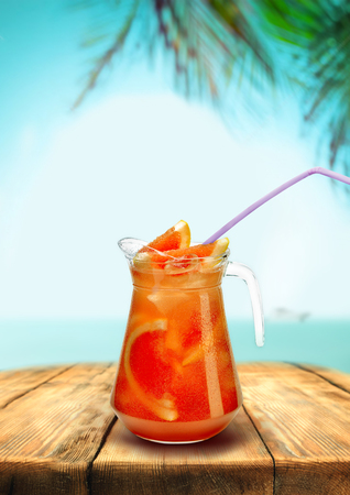Lemonade beach bar pub, red grapefruit drink with straw wooden table, background of palm trees sea letnegeo.の写真素材