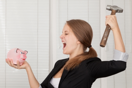girl  about to break his piggy bank with hammer の写真素材