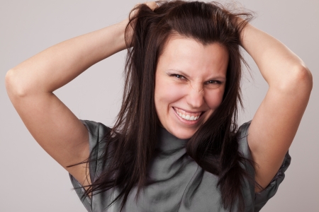 happy young attractive woman holding her hair on a grey backgroundの写真素材
